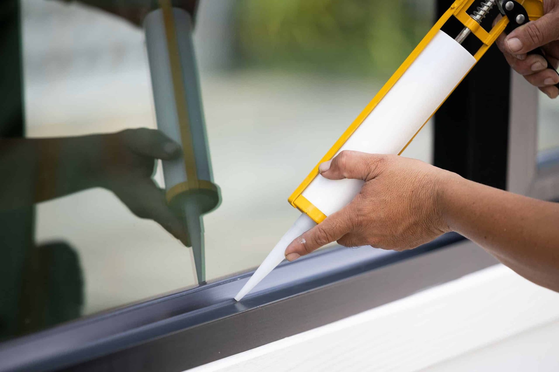 Technician applying exterior caulk around a window in Media, PA