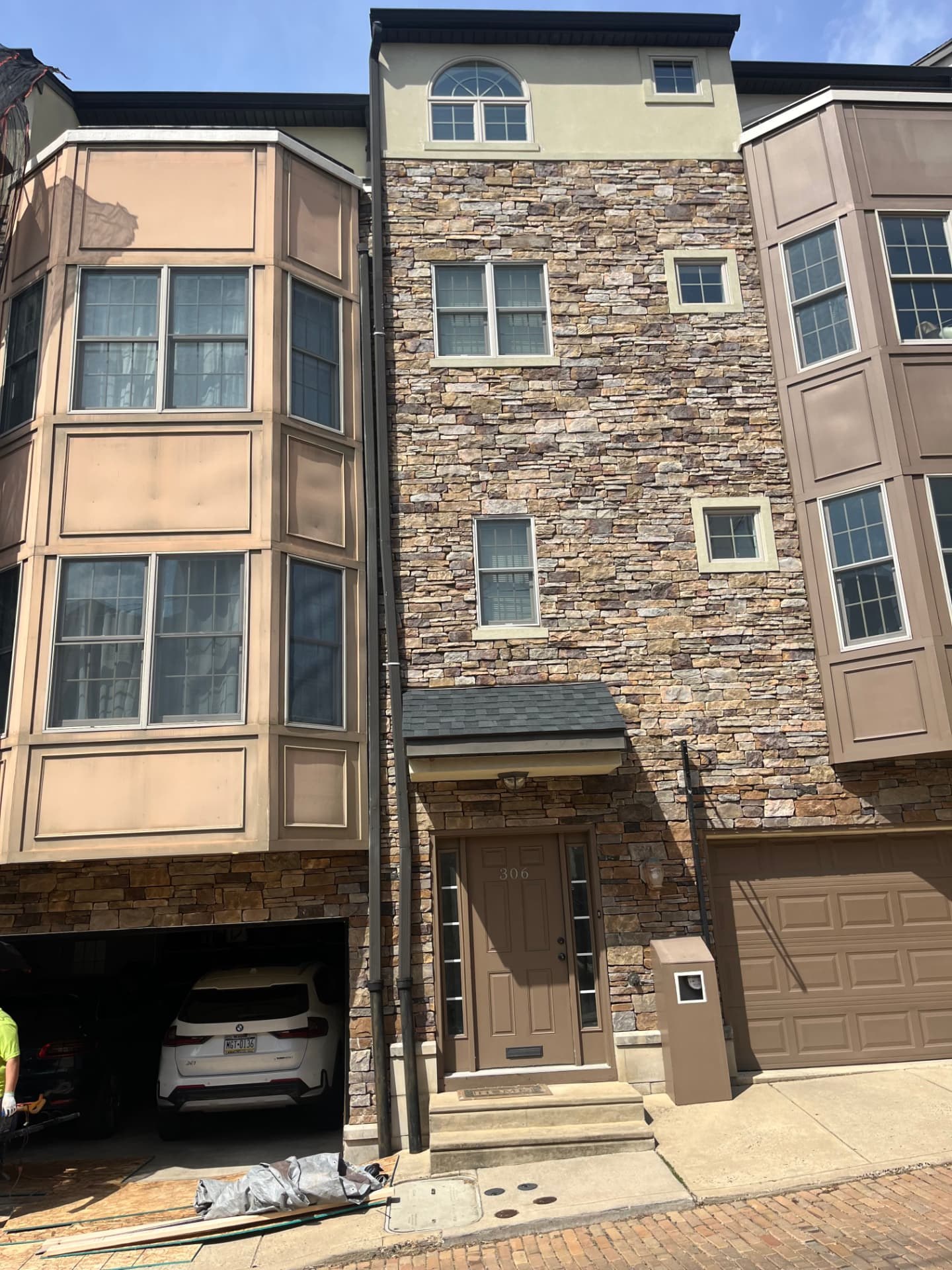 Mason installing natural stone veneer on a home facade near Media, PA
